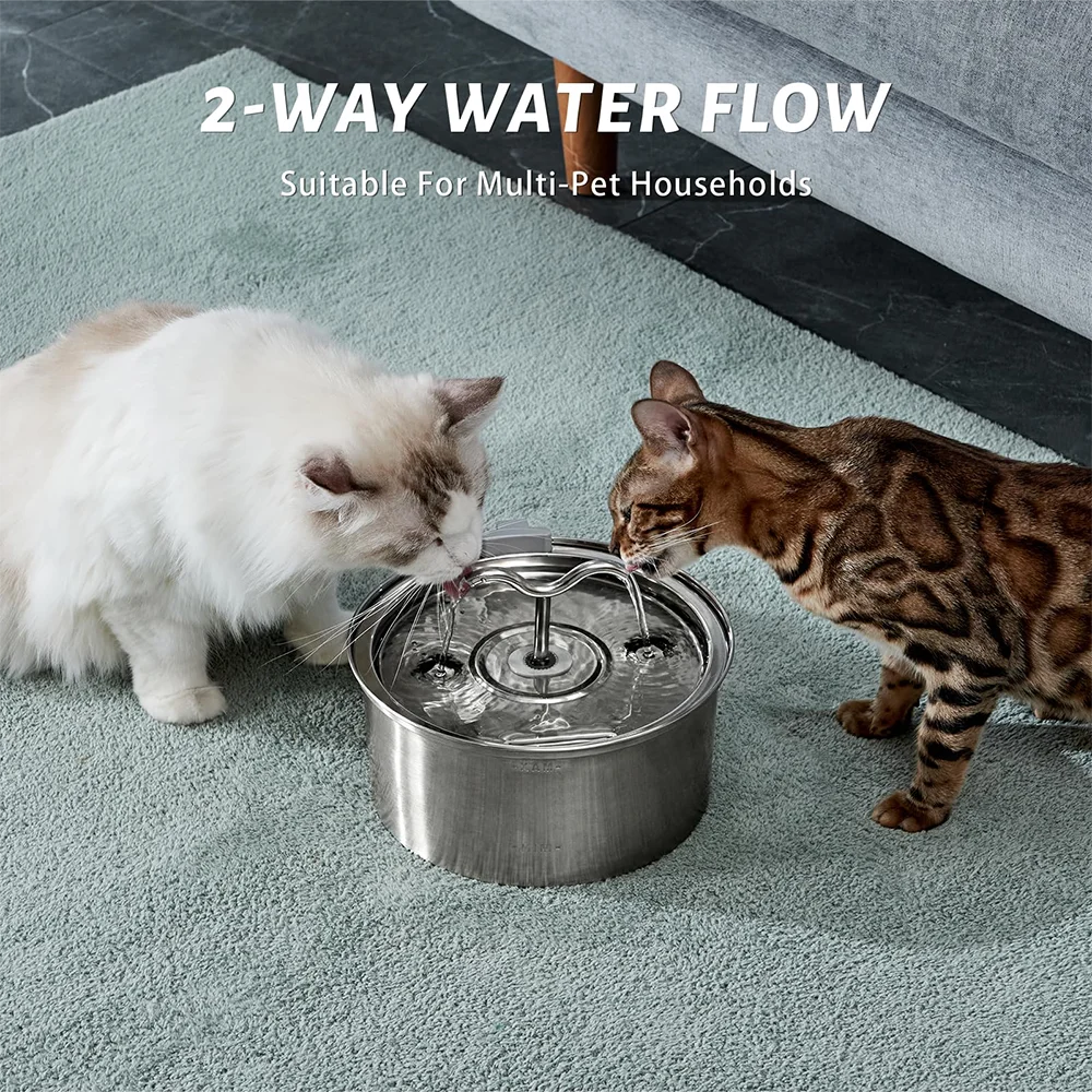 Two cats drinking from a stainless steel water fountain with '2-Way Water Flow' text above.